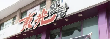 가게 건물 윗부분 — 흰 외벽의 붉은 간판 «東光알탕»과 보라색 창틀